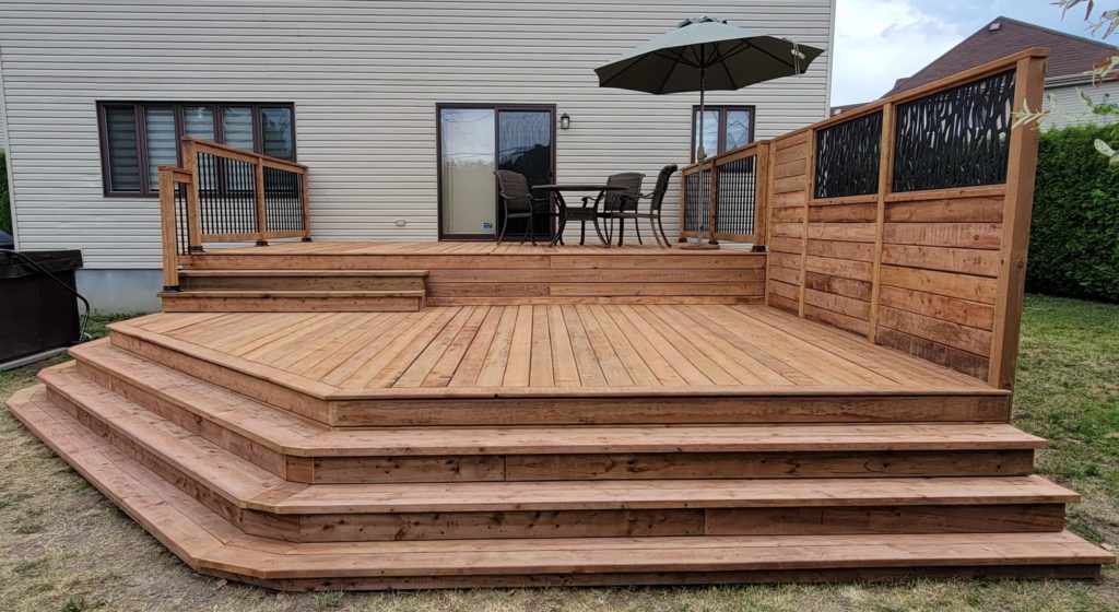 Treated lumber deck, railing made of wood and black metal balusters, and stairs down to the lawn. 